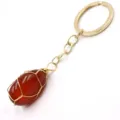 Close-up of a wire-wrapped red gemstone keychain, detailed view of the gold chain and stone pendant. - 3-Section Chain / Red Agate