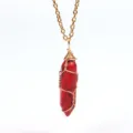 Nahaufnahme des roten hexagonalen Kristallanhängers mit filigraner goldener Drahtwicklung. - Gold Roter Stein