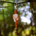 Detailaufnahme eines Rohelement-Kristalls im orangefarbenen Makramee-Netzanhänger für Schlüssel. - Weißer Kristall Anhänger / Weiß Kristall