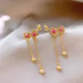 Dettaglio di squisiti orecchini floreali a catena lunga con pietre rosa scintillanti. - Nappa di Fiori di Pruno / Oro