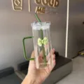 Gros plan détaillé de la tasse en verre carrée transparente esthétique avec nœud papillon vert. - Vert