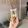 Tasse en verre carrée transparente avec nœud, poignée et paille élégante pour café ou lait. - Jaune