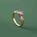 Elegante vergulde ring met een sprankelende paarse zirkonia en gedraaid bandontwerp. - Paars(SE1504)
