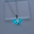 Detailaufnahme einer leuchtenden Schildkröten Halskette mit blauem Nachtleuchteffekt Anhänger. - Blau-Grünes Leuchten / Silber (NY727)