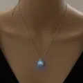 Detailed view of a silver pug dog cage pendant necklace with a glowing luminous bead. - Pug Dog-Sky Blue Glow