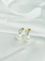 Close-up detail of elegant gold-toned zircon and faux pearl stud earrings on white silk. - Egg Shaped Gold