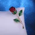 Elegant red fabric rose brooch featuring green enamel leaves and gold tone stem - Burgundy