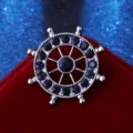 Detailed close-up of a silver nautical ship wheel brooch set with dark blue rhinestones. - Dark Blue Rhinestone on Gun Black Base / Gunmetal