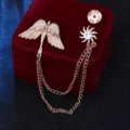 Close-up detailweergave van de goudkleurige engelenwleugel en zonkettingbroche met fonkelende strass. - Goud met kleine zon