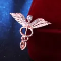 Nahaufnahme Detail der roségoldenen Kaddukus Schlangen und Flügel Strass Brosche Zubehör. - Roségold