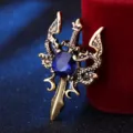Vista detallada de broche retro de espada de doble dragón con gema de cristal azul central. - Oro antiguo