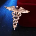 Detailaufnahme der goldenen Caduceus Brosche mit kunstvoll gestalteten filigranen Flügeln. - Gold