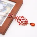 Gros plan sur un pendentif de front en strass rouge, chaîne dorée avec cristaux étincelants. - Rouge