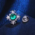 Nahaufnahme einer gotischen Kristall-Kreuz-Brosche Kragennadel mit grünem Stein. - Silber mit grünem Strass