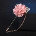 Gros plan d'une broche fleur en tissu rose avec longue épingle et chaîne dorée. - Rose