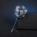 Gros plan détaillé d'une broche fleur en tissu gris avec longue épingle métal, chic. - Bleu clair