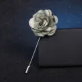 Gros plan d'une broche élégante en tissu gris en forme de fleur avec longue épingle. - Vert