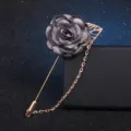 Grey fabric flower brooch detail closeup, featuring long pin, hollow leaf and tassel chain. - Gray