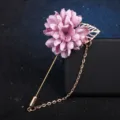 Gros plan d'une broche fleur en tissu rose avec feuille d'or, longue épingle et chaîne élégante. - Mauve Clair