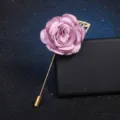 Detailed view of elegant fabric rose flower brooch with gold leaf and long stick pin accessory. - Purple