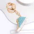Detailansicht eines goldfarbenen Turnschuh-Schlüsselanhängers mit blauen Strasssteinen - Canvas Schuh Schlüsselanhänger / Blau