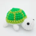 Detaillierte Nahaufnahme eines süßen handgehäkelten grün-weißen Schildkröten-Anhängers - 8.5cm / Puppen-Stil / Grün
