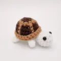 Detaillierte Makroansicht eines süßen, handgefertigten Häkel-Schildkröten-Anhängers. - 7cm / Puppen-Stil / Braun