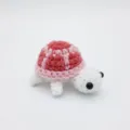 Detail einer handgemachten rosa-weißen Häkelschildkröte aus strukturiertem Garn - 7cm / Puppen-Stil / Rosa