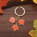 Herbst Ahornblatt Schlüsselanhänger mit drei orangefarbenen Emaille-Blättern und Goldring. - Orange