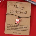 Weihnachts-Wunscharmband mit niedlichem Weihnachtsmann-Anhänger auf Kraftpapier-Displaykarte. - SRY297-1