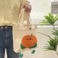 Cute canvas tote bag with cartoon orange design, casual shoulder handbag for daily use. - Red Apple Little Man Handbag / Beige