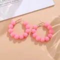 Nahaufnahme von trendigen rosa Perlen-Creolen, süßes Bonbon-Design für schicken Alltag. - Rosa