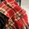Detalle de bufanda de cuadros rojos con textura de invierno acogedora y patrón festivo clásico. - Paz y Alegría