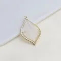 Close-up detail of a gold metal leaf shaped pendant with delicate white string weaving inside. - White