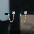 Gedetailleerde close-up van glanzende vergulde kettingoorringen met zirkoon en blauwe stenen. - Stijl 1 / Goud