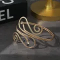 Prachtige goudkleurige open armband met spiraalvormige uitsnede en strass-steentjes. - Spiraalvormige Stroomlijnstijl / Goud