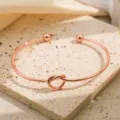 Close-up van de roségouden knooparmband die de verfijnde metalen textuur prachtig laat zien. - Roségoud
