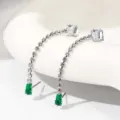 Elegante lange kristallen kwast oorhanger met groene zirkoniaste S, detailweergave. - Witgoud met groene & witte zirkonia