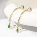 Detailopname van lange vergulde zirkonia oorbellen met groene steenhangers. - Groene & witte zirkonia met 20K echt goud verguld