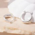 Close-up of thick silver-tone hoop earrings on natural stone display surface, chic minimalist jewelry detail shot. - S925 Silver