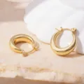 Close-up detail of minimalist chunky gold hoop earrings on textured stone surface with ceramic prop. - 18K Gold