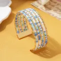 Meerlaagse kralen manchetarmband met blauw witte rocailles en gouden metalen stangen - Driekleur 3 / Goud
