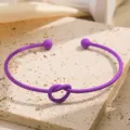 Close-up van de paarse metalen manchetarmband met een fijn knoopje en bolvormige uiteinden. - Donkerviolet