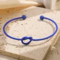 Blauwe open armband met elegant knoopdetail en gladde bolletjes voor moderne damessieraden. - Donkerblauw