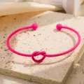 Close-up detail van de roze metalen knoop manchet armband met matte afwerking en open. - Rozerood