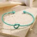 Detailopname van de mintgroene metalen open armband met knoopontwerp en bal-einden voor stijl. - Meerblauw