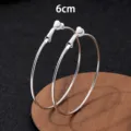 Gedetailleerd overzicht van grote zilveren creoolse oorbellen van 6cm, met gepolijste metaalstructuur. - Clip-On Earrings / 6cm / Zilver