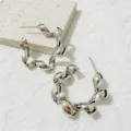 Gedetailleerd close-up van zilveren gedraaide oorringen met een uniek spiraalvormig ontwerp. - Stijl 4 Zilver