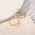 Detail van vergulde creolen, glanzend gepolijst metaaloppervlak en een veilige sluiting. - 30mm / Goud