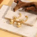 Gedetailleerd opname van luxe gouden metalen oorbellen met een uniek dubbel kralenontwerp. - Stijl A006 / Goud